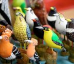 Rzeźby ptaszków wykonane z drewna. Widzimy dudki, sokoła, dzięcioła, srokę i inne gatunki. Ptaszki są pomalowane kolorowymi farbami.