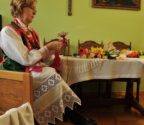 Marianna Pokora w swoim mieszkaniu. Kobieta wykonuje kwiat z bibuły. Na stole leżą jej prace. Na ścinie wisi duży krzyż i obraz z Chrystusem.