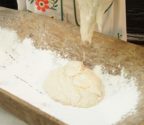 Ciasto na chleb w grewnianym naczyniu - kopańce, wypełnionym mąką.