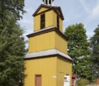 Drewniana dzwonnica z trzema kondygnacjami. Jej szczyt wieńczy ażurowa kopułka z krzyżem.Dzwonnica jest oszalowana i pomalowana na żółty kolor. Stoi pośród drzew.
