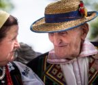 Starsza kobieta i mężczyzna w strojach tradycyjnych podczas rozmowy.