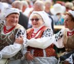 Uczestnicy festiwalu. Na pierwszym planie starsze kobiety w strojach wilanowskich. Na głowie mają białe chusty czepcowe. Ich koszule są wyszywane czarnym haftem o motywach kwiatowych. 