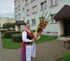 Czesława Lewandowska przed swym blokiem w Ostrołęce. W rękach trzyma kwiaty z bibuły.
